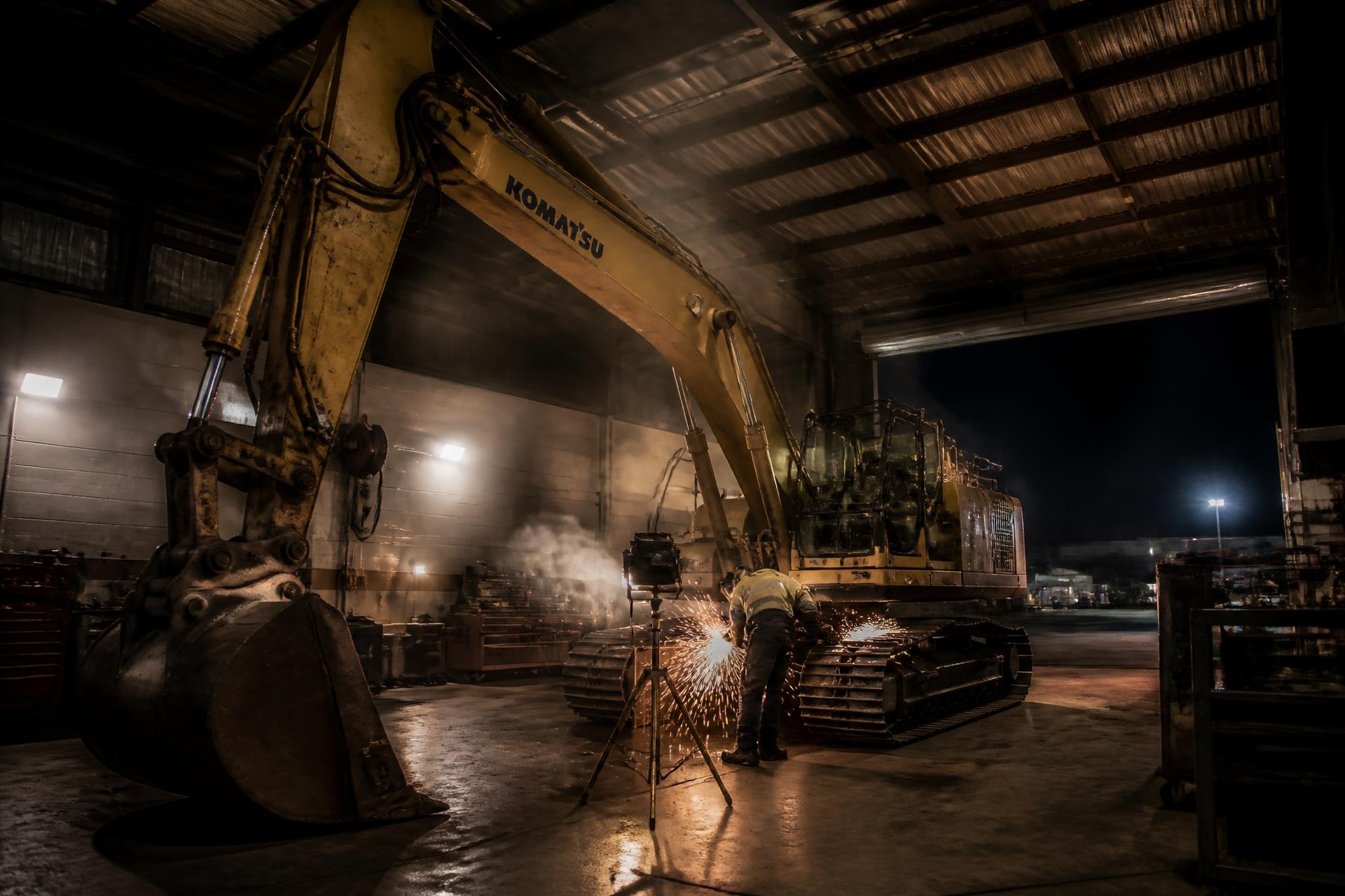 Technician servicing a tracked excavator inside the Elite Heavy Equipment Repair shop